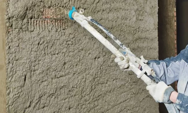Aplicação de chapisco com máquina de projeção em parede de obra