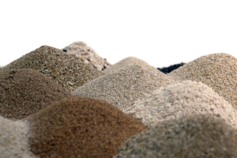 Montes de pó de pedra e agregados finos com diferentes granulometrias sobre fundo branco